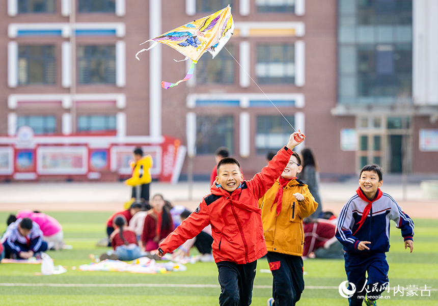 呼和浩特市玉泉区恒昌店巷小学五里营校区的学生在操场上放飞风筝，感受春天的气息。丁根厚摄