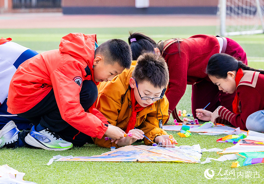 呼和浩特市玉泉區恆昌店巷小學五裡營校區的學生在操場上彩繪風箏，感受傳統文化魅力。丁根厚攝