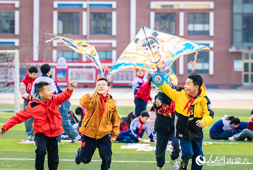 呼和浩特市玉泉區恆昌店巷小學五裡營校區的學生在操場上放飛風箏，感受春天的氣息。丁根厚攝