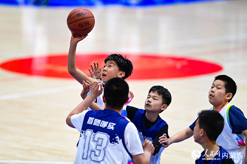 3月25日，呼和浩特市赛罕区腾飞路小学队球员（左）在比赛中投篮。王正摄