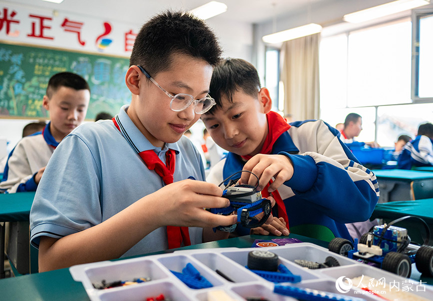 3月26日，呼和浩特市玉泉区通顺街小学机器人社团的学生在调试组装乐高机器人。丁根厚摄