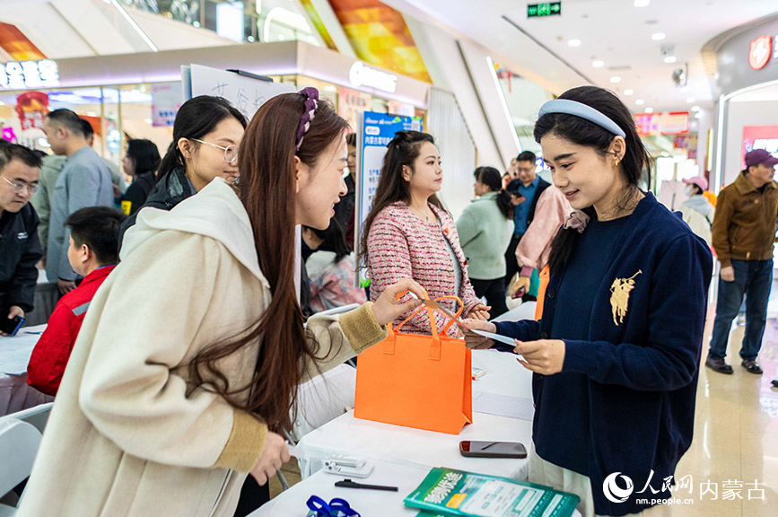 3月28日，呼和浩特市玉泉区“春风行动”暨就业援助季专场招聘会现场，工作人员（左）向求职者介绍岗位信息。丁根厚摄