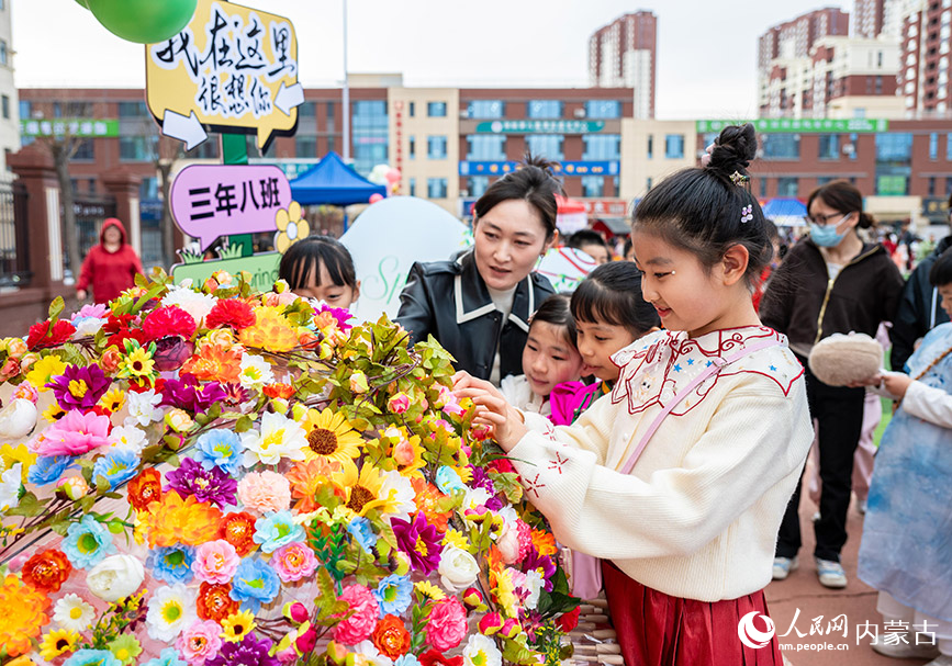 3月27日，呼和浩特市新城区北垣小学新雅校区第四届校园风筝节活动现场，学生们在装扮花伞。丁根厚摄