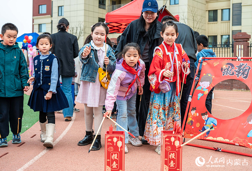 3月27日，呼和浩特市新城区北垣小学新雅校区第四届校园风筝节活动现场，学生们在玩投壶游戏。丁根厚摄