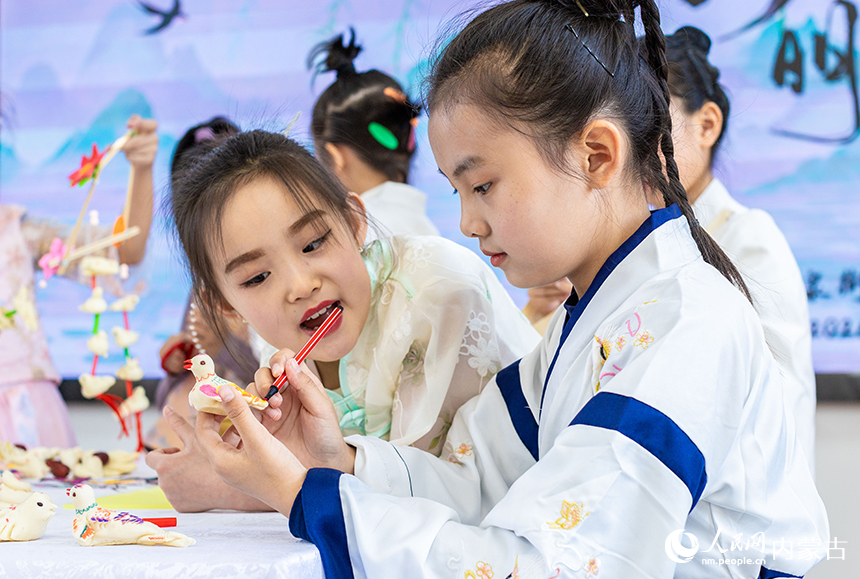 呼和浩特市玉泉区清泉街小学清明节主题活动现场，学生们在彩绘面塑“寒燕”。丁根厚摄