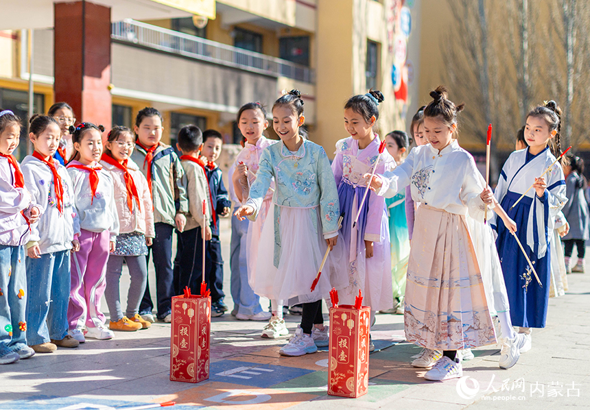呼和浩特市玉泉区清泉街小学清明节主题活动现场，学生们在玩投壶游戏。丁根厚摄