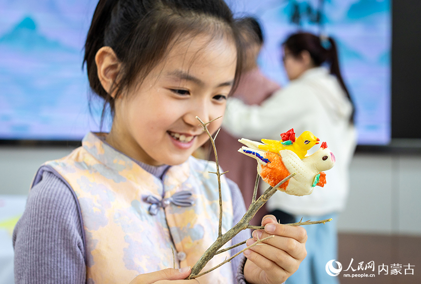 呼和浩特市玉泉区清泉街小学清明节主题活动现场，学生展示制作的“春燕护雏”面塑作品。丁根厚摄