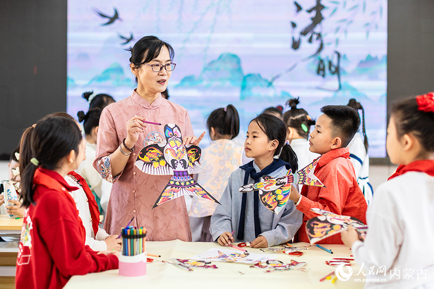 呼和浩特市玉泉区清泉街小学清明节主题活动现场，老师在为学生们讲解清明时节放风筝的习俗。丁根厚摄