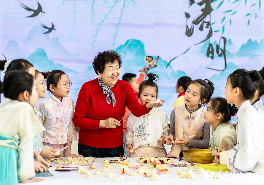呼和浩特市玉泉区清泉街小学清明节主题活动现场，学生们在民间艺人的指导下学习制作面塑“寒燕”。丁根厚摄