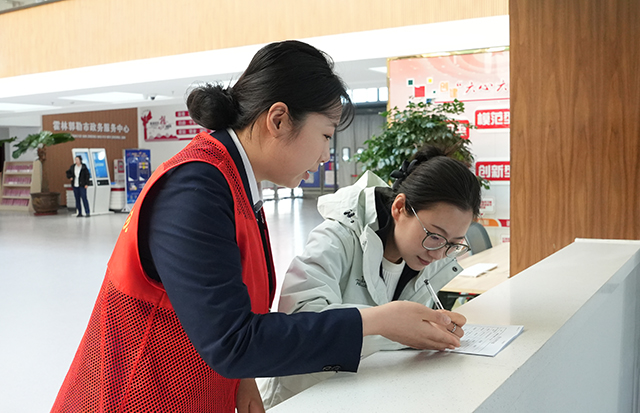（↑政务服务大厅帮办代办人员为办事群众讲解填表要求。郎静波摄）