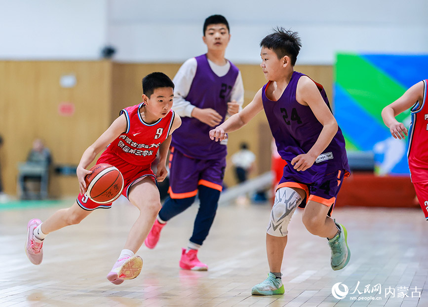 4月9日，内蒙古师范大学附属第三学校队球员（左）在小学男子组比赛中运球突破。丁根厚摄