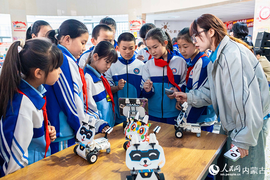 呼和浩特市玉泉区通顺街小学第一届科技节活动现场，学生们与四足机器人互动。丁根厚摄