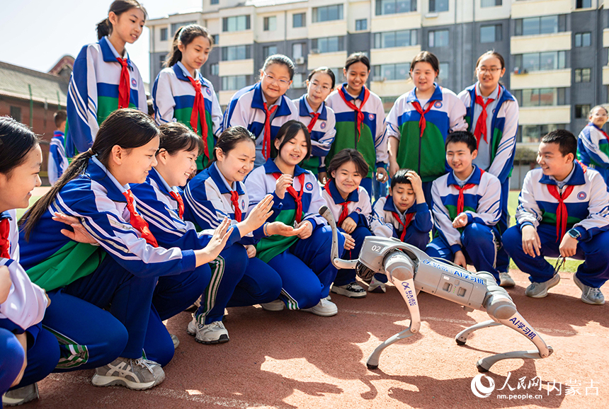 呼和浩特市玉泉区通顺街小学第一届科技节活动现场，学生们与机器狗开心互动。丁根厚摄