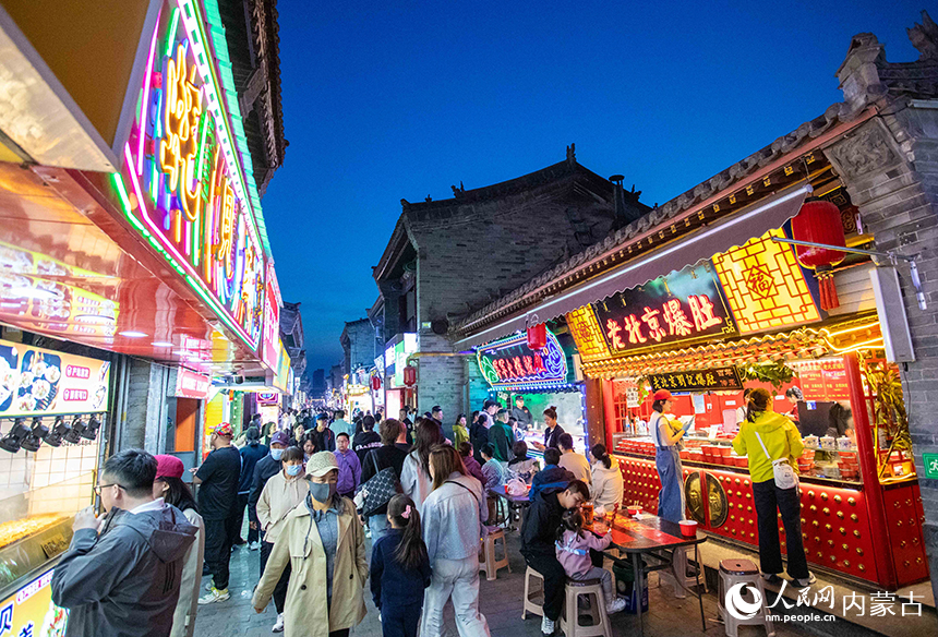 游客在呼和浩特市玉泉区塞上老街旅游休闲街区“通顺大巷夜市”游玩。丁根厚摄