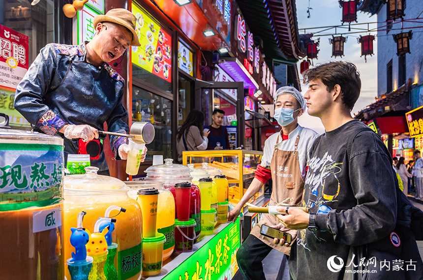 外国游客在呼和浩特市玉泉区塞上老街旅游休闲街区选购果茶。丁根厚摄