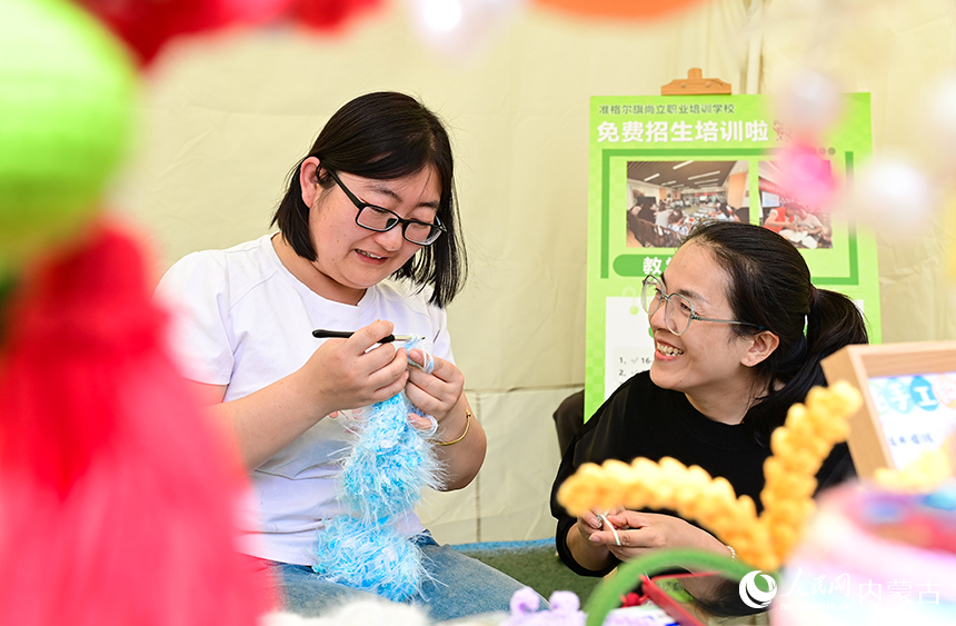 游客在鄂尔多斯市准格尔旗美稷·长河里夜未央文化街区体验手工毛线钩织技艺。王正摄