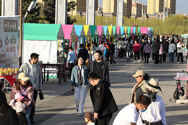 市集區域，彩色帳篷攤位一字排開，市民游客穿梭其間，在煙火氣十足的市集裡，感受草原夜市的熱鬧與活力。 