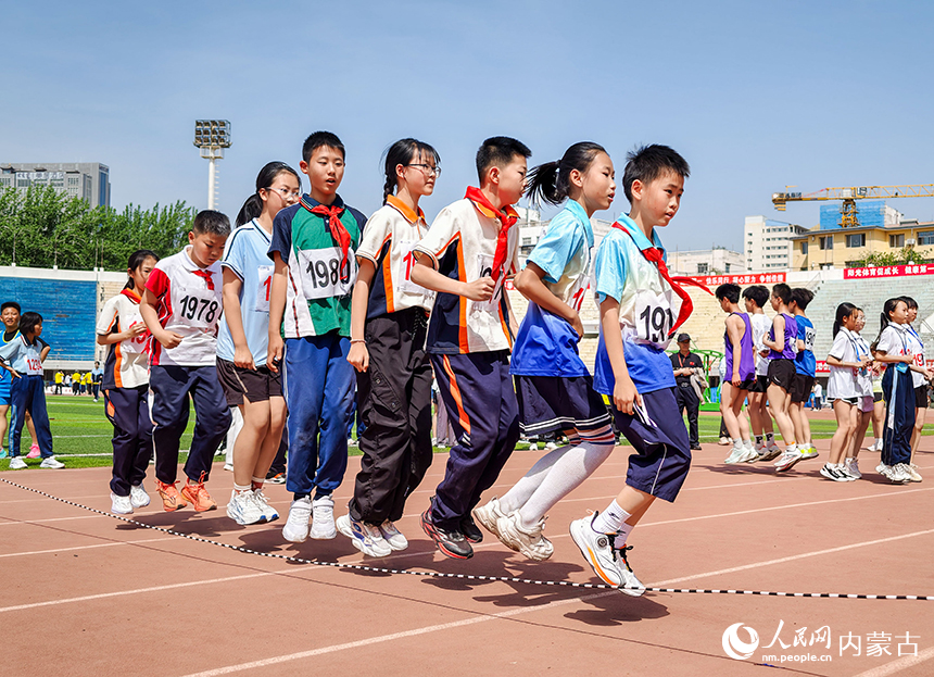 参赛小选手在呼和浩特市玉泉区中小学生田径运动会集体跳绳比赛中展开激烈比拼。丁根厚摄