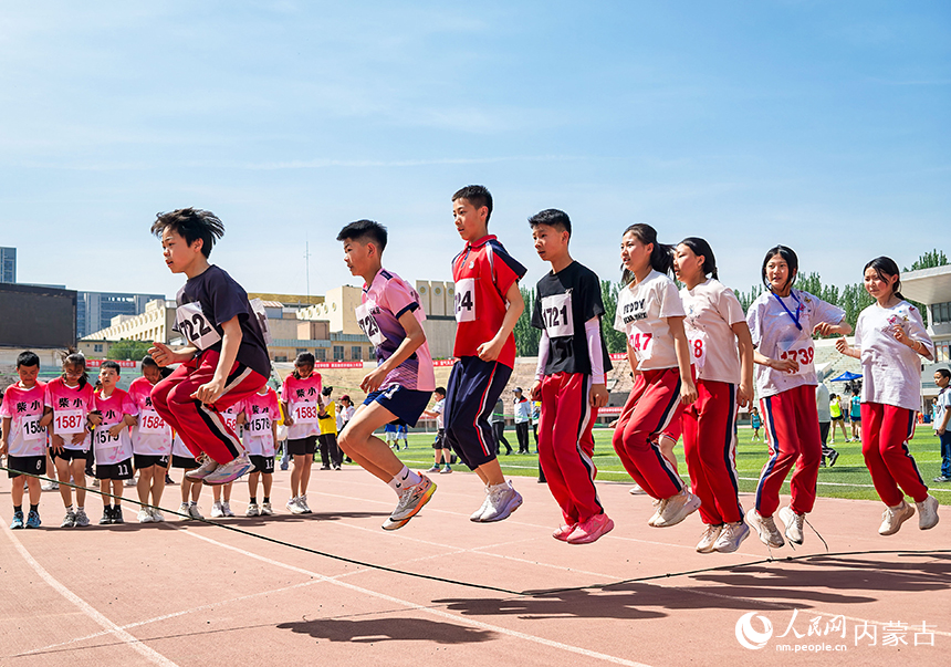 参赛小选手在呼和浩特市玉泉区中小学生田径运动会集体跳绳比赛中展开激烈比拼。丁根厚摄