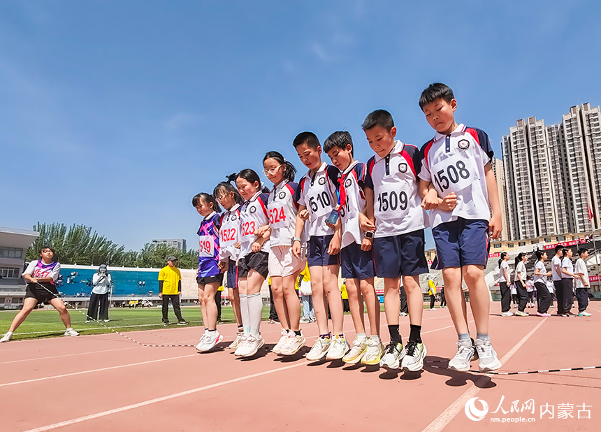 参赛小选手在呼和浩特市玉泉区中小学生田径运动会集体跳绳比赛中展开激烈比拼。丁根厚摄