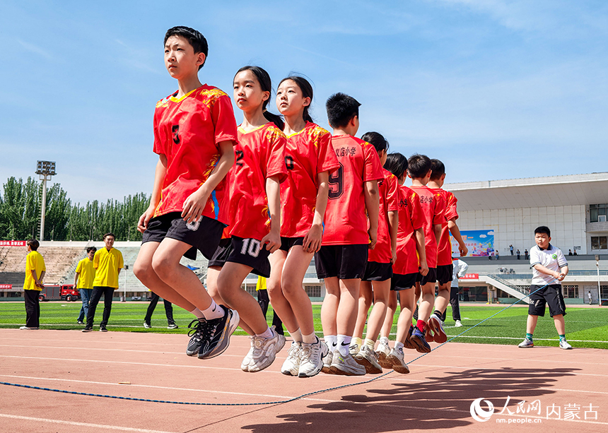 參賽小選手在呼和浩特市玉泉區中小學生田徑運動會集體跳繩比賽中展開激烈比拼。丁根厚攝