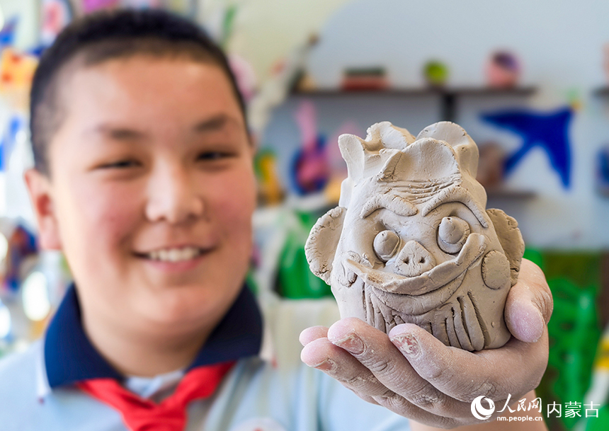 呼和浩特市玉泉区西菜园小学陶艺社团学生在展示制作的陶艺作品《奇特的脸》。丁根厚摄