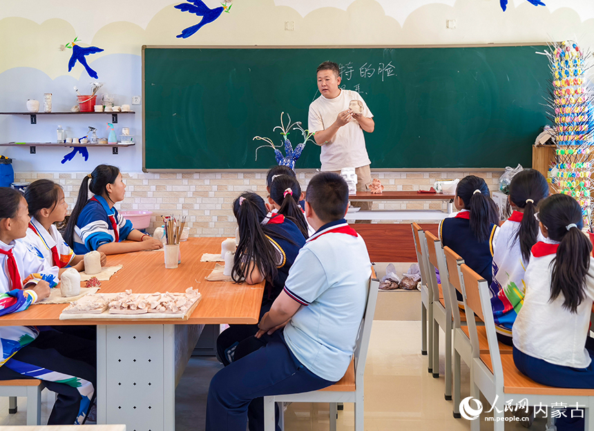 呼和浩特市玉泉区西菜园小学陶艺社团教师为学生讲解陶艺基础技法。丁根厚摄