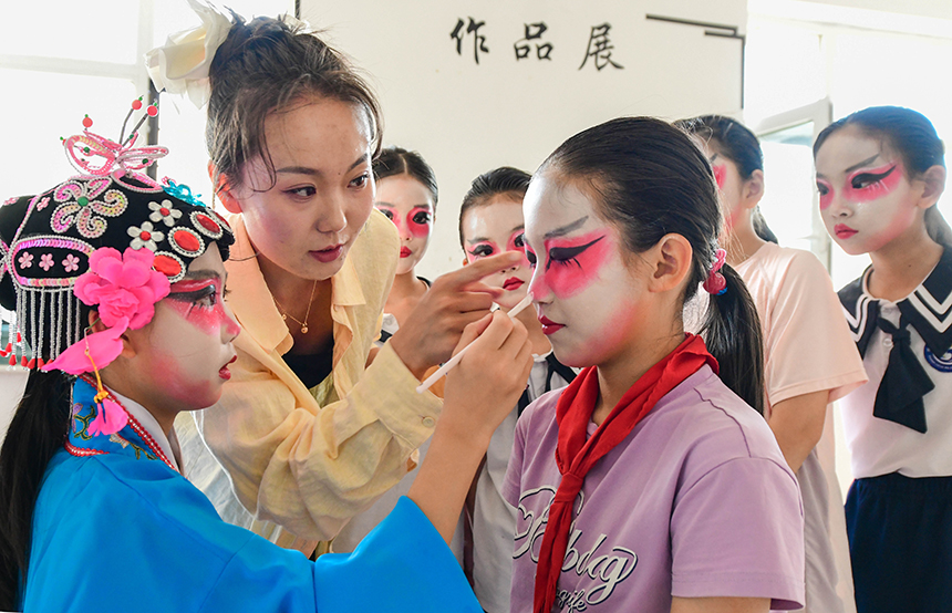 呼和浩特市賽罕區巨華第二小學教師劉馨月指導京劇社團小演員化妝。王正攝