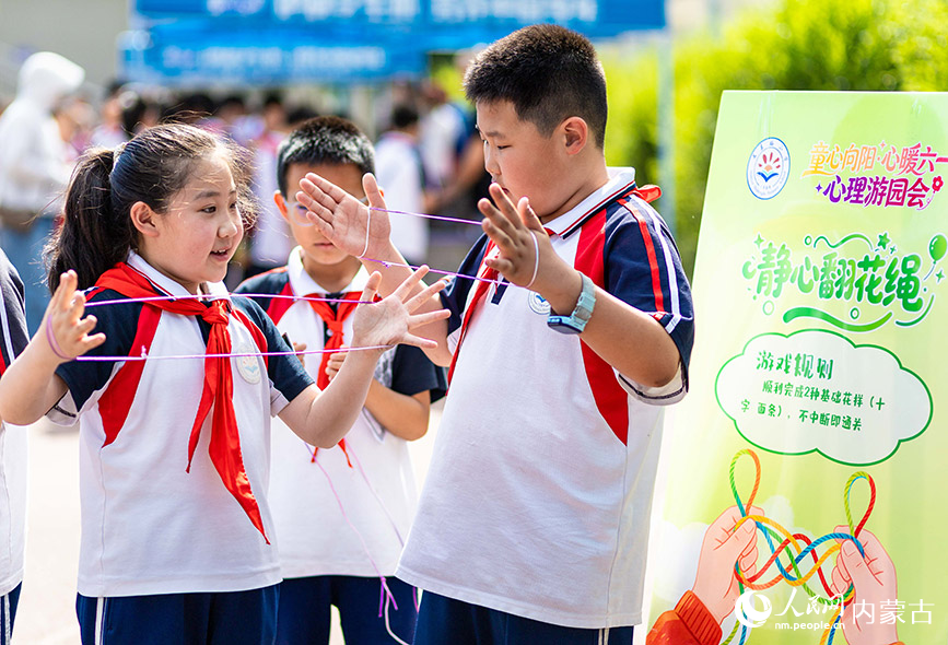 5月29日，內蒙古呼和浩特市玉泉區石東路小學學生在操場上參加“翻花繩”趣味游戲，歡慶“六一”國際兒童節。丁根厚攝