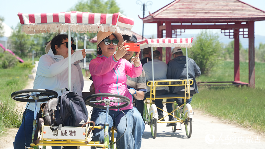 乌兰察布市岱海湖畔，游客们骑着观光自行车游览湖光春色。近年来，随着岱海生态综合治理成效显著，湖区周边生态环境持续改善，优美的自然风光吸引了众多游客前来休闲观光。人民网记者 张力洋摄