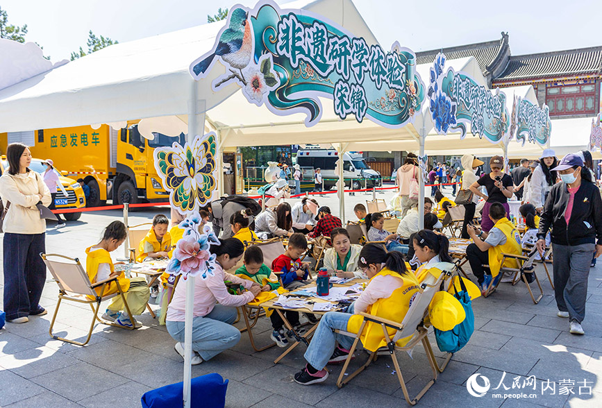 6月13日，家长带领孩子们在“文化和自然遗产日”活动现场参加非遗研学体验活动。丁根厚摄