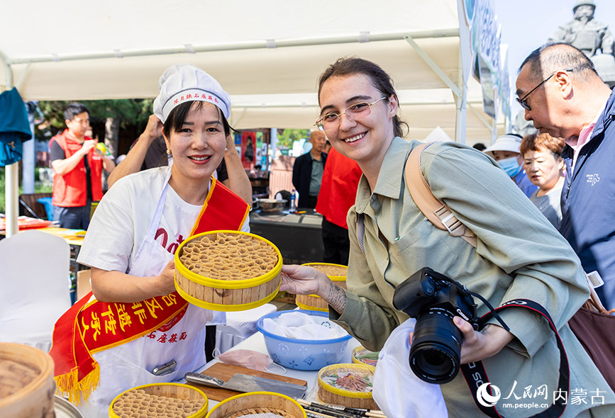 6月13日，外国游客在“文化和自然遗产日”活动现场与莜面饮食制作技艺传承人留影。丁根厚摄