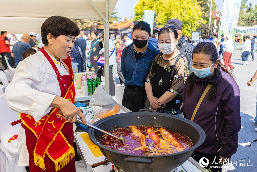 6月13日，游客在“文化和自然遗产日”活动现场了解托县炖鱼技艺。丁根厚摄