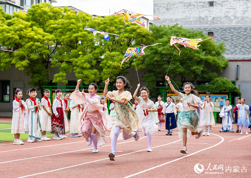 呼和浩特市玉泉区五塔寺东街小学“我们的节日·端午”主题活动现场，学生们在操场上放飞纸鸢。丁根厚摄