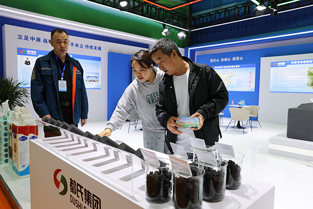(市民驻足产品展区,细致观摩了解铝用预焙生阳极产品样品。美丽摄)