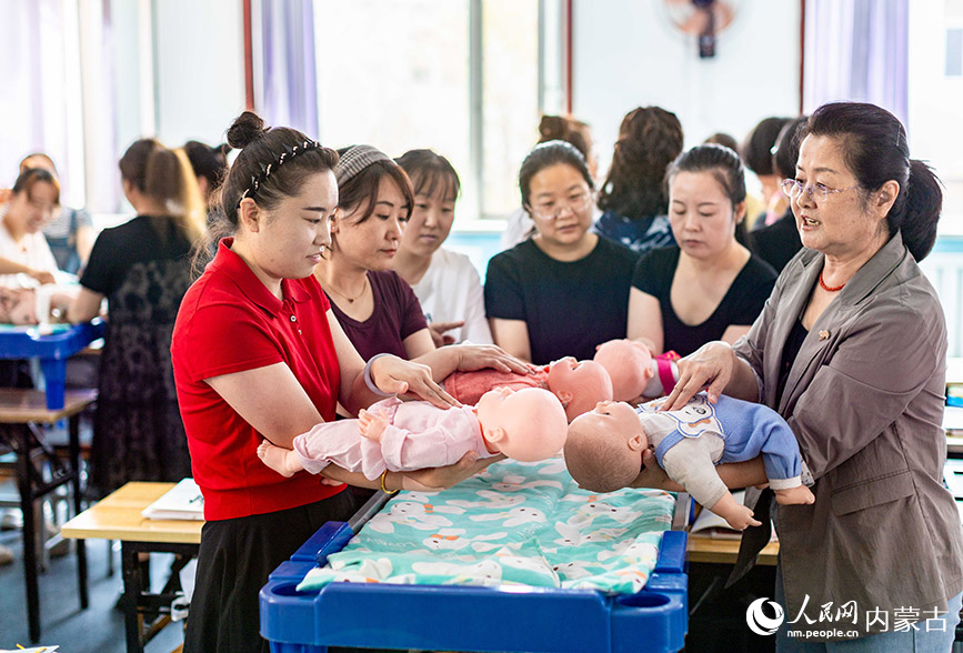 7月9日，在呼和浩特市玉泉区内蒙古扬帆职业培训学校，学员们在练习婴幼儿护理。丁根厚摄