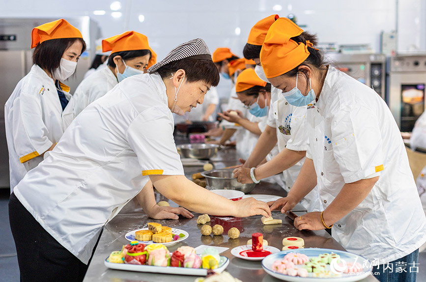 7月9日，在呼和浩特市玉泉区内蒙古扬帆职业培训学校，学员们在老师（左三）指导下学习制作面点。丁根厚摄