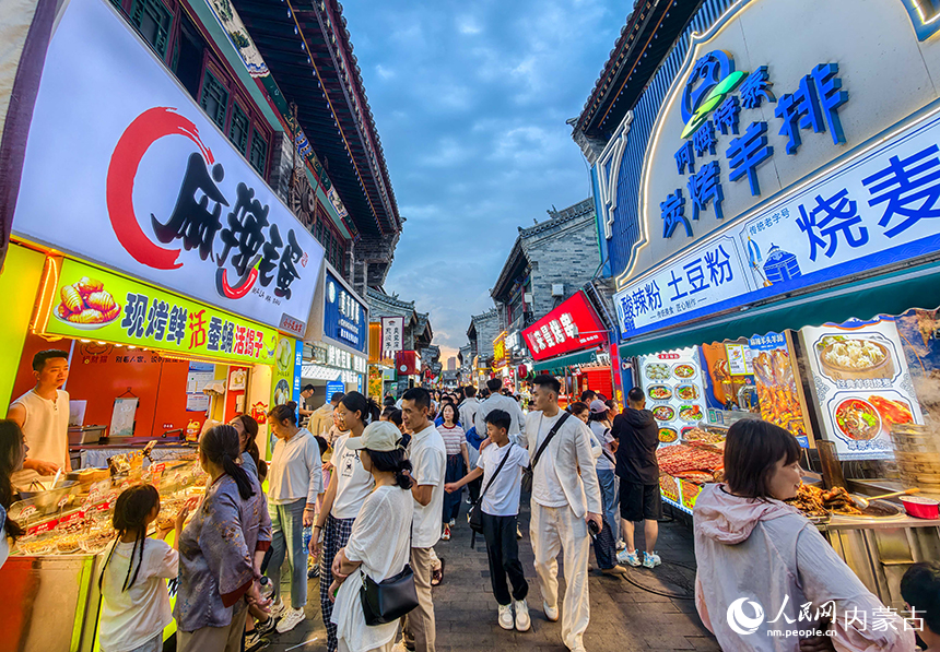 呼和浩特市玉泉区塞上老街旅游休闲街区，游客在夜市品尝特色小吃。丁根厚摄