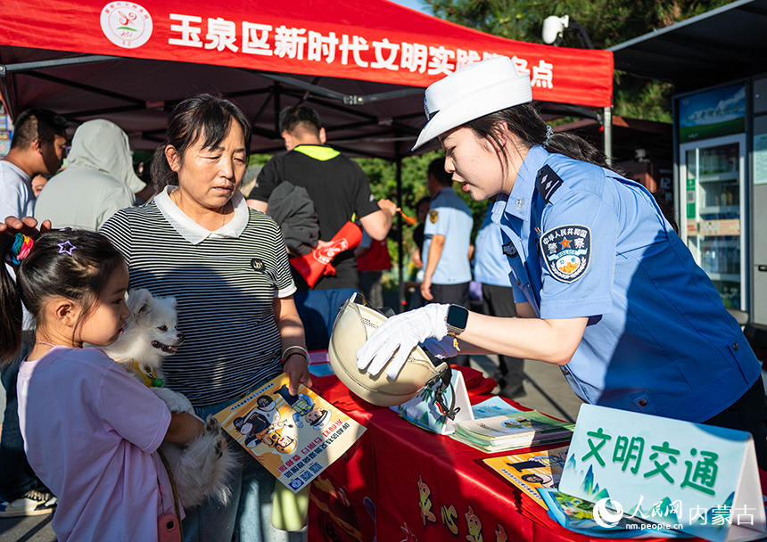 呼和浩特市玉泉區“文明市集”活動現場，交警向市民普及安全頭盔佩戴知識。丁根厚攝