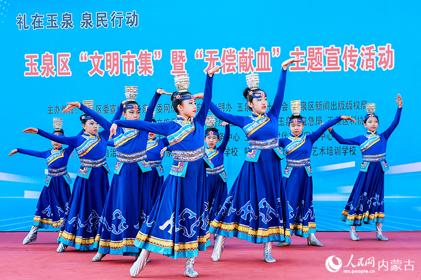 呼和浩特市玉泉区“文明市集”活动现场，文艺志愿者为市民献上舞蹈表演。丁根厚摄