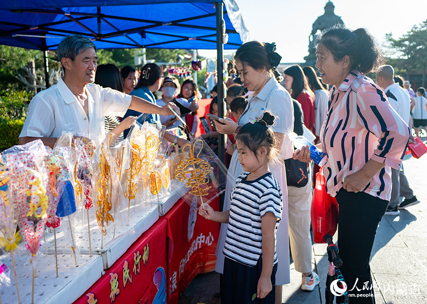 呼和浩特市玉泉区“文明市集”活动现场，市民在选购非遗糖画。丁根厚摄