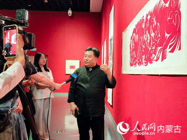 中国剪纸(和林格尔剪纸)国家级代表性传承人段建珺向媒体介绍作品。实习生 张美茹摄