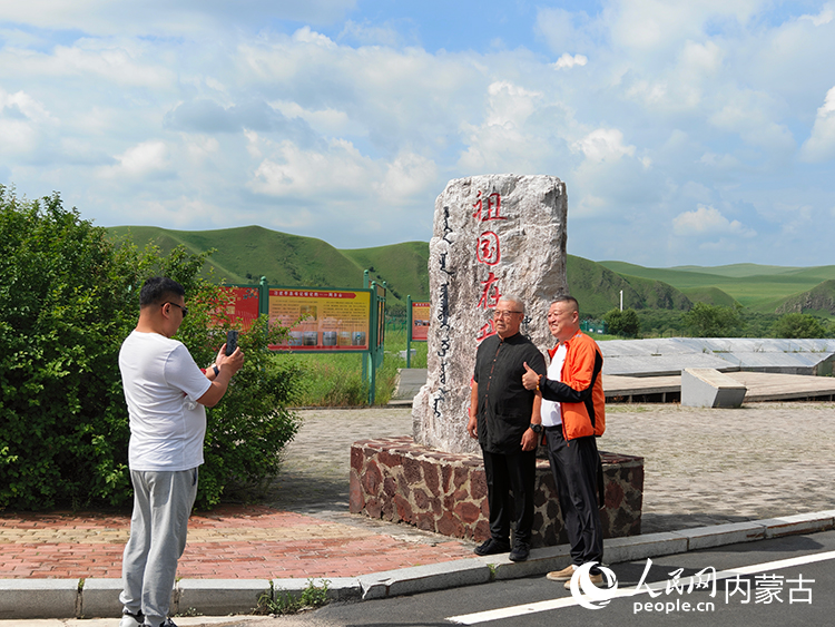 来阿尔山旅游的游客在国门前拍照留念。人民网记者 赵梦月摄