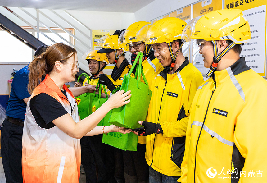 内蒙古呼和浩特市玉泉区总工会“夏日送清凉”慰问活动现场，志愿者为外卖骑手送上防暑降温礼包。丁根厚摄