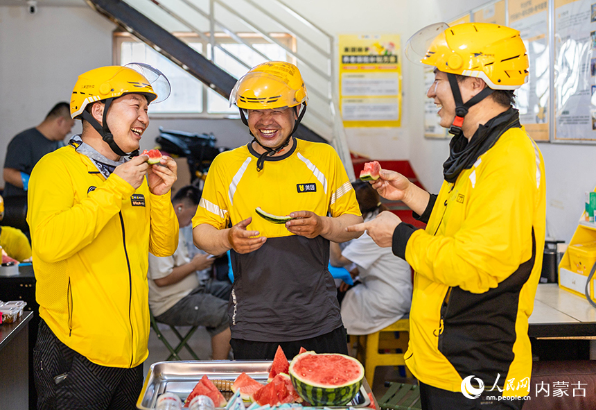 内蒙古呼和浩特市玉泉区总工会“夏日送清凉心”慰问活动现场，外卖骑手正在吃西瓜。丁根厚摄