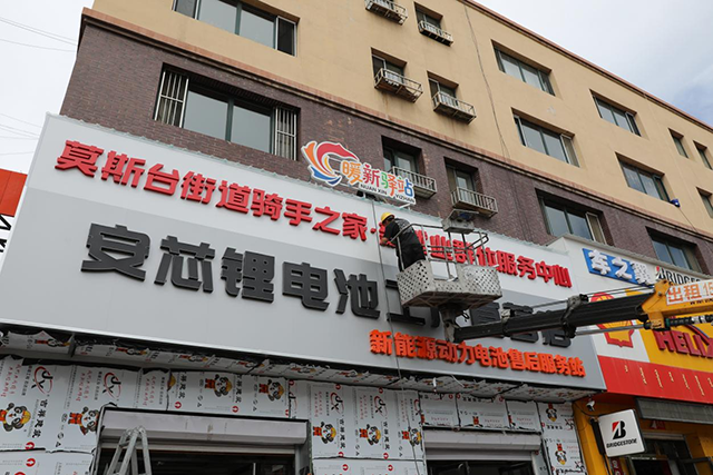 (↑工人們安裝“暖新驛站”標識 閆冬雪 攝)