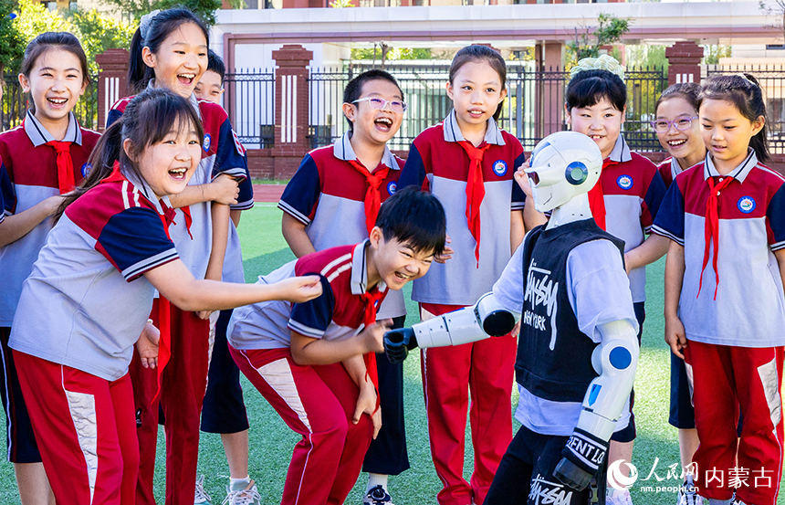 呼和浩特市新城區北垣小學新雅校區學生們與人形機器人互動。丁根厚攝