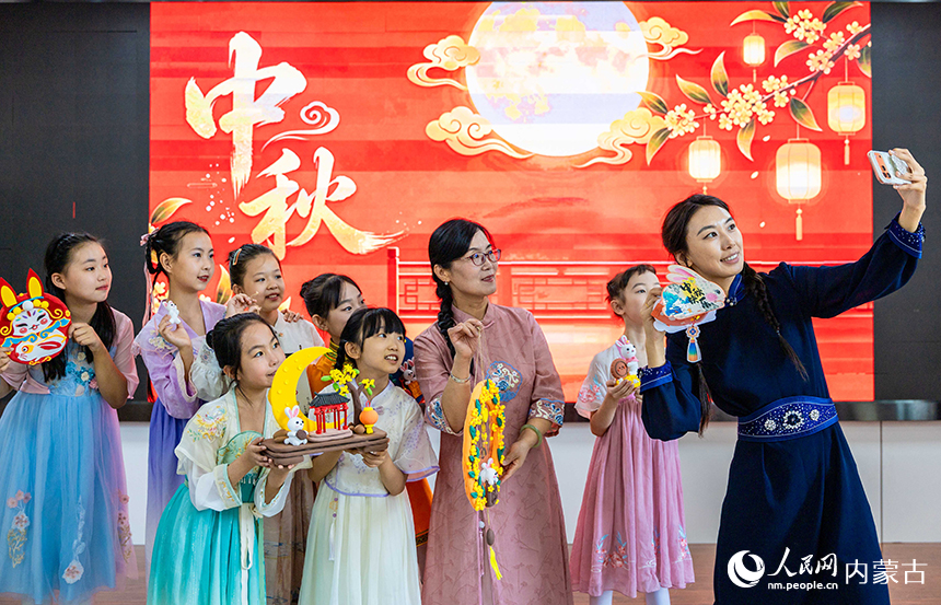 呼和浩特市玉泉区清泉街小学“品民俗 迎中秋”主题活动现场，老师和学生们手持中秋手工作品自拍留影。丁根厚摄