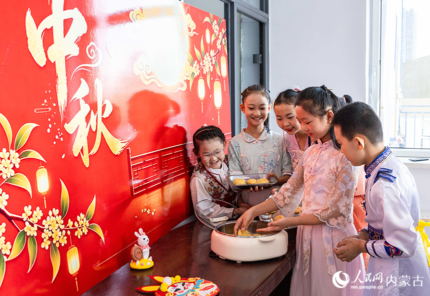 呼和浩特市玉泉区清泉街小学“品民俗 迎中秋”主题活动现场，学生们在烤制传统月饼。丁根厚摄
