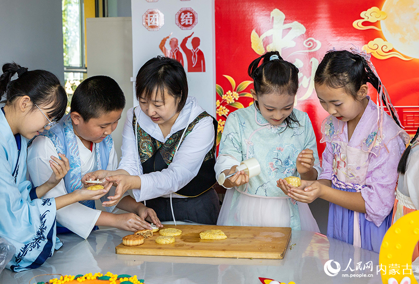 呼和浩特市玉泉区清泉街小学“品民俗 迎中秋”主题活动现场，师生们在制作传统月饼。丁根厚摄